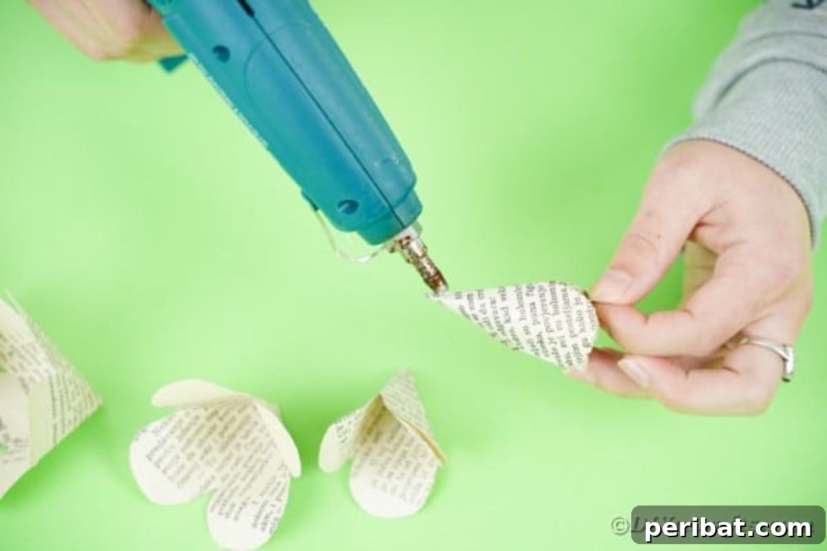 Hands applying hot glue to the petals of a paper flower piece