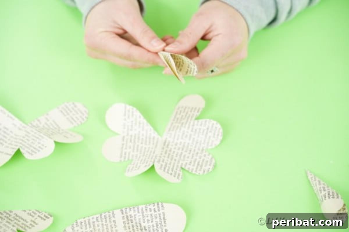 Hands folding and gluing a multi-petal paper piece to create a flower shape