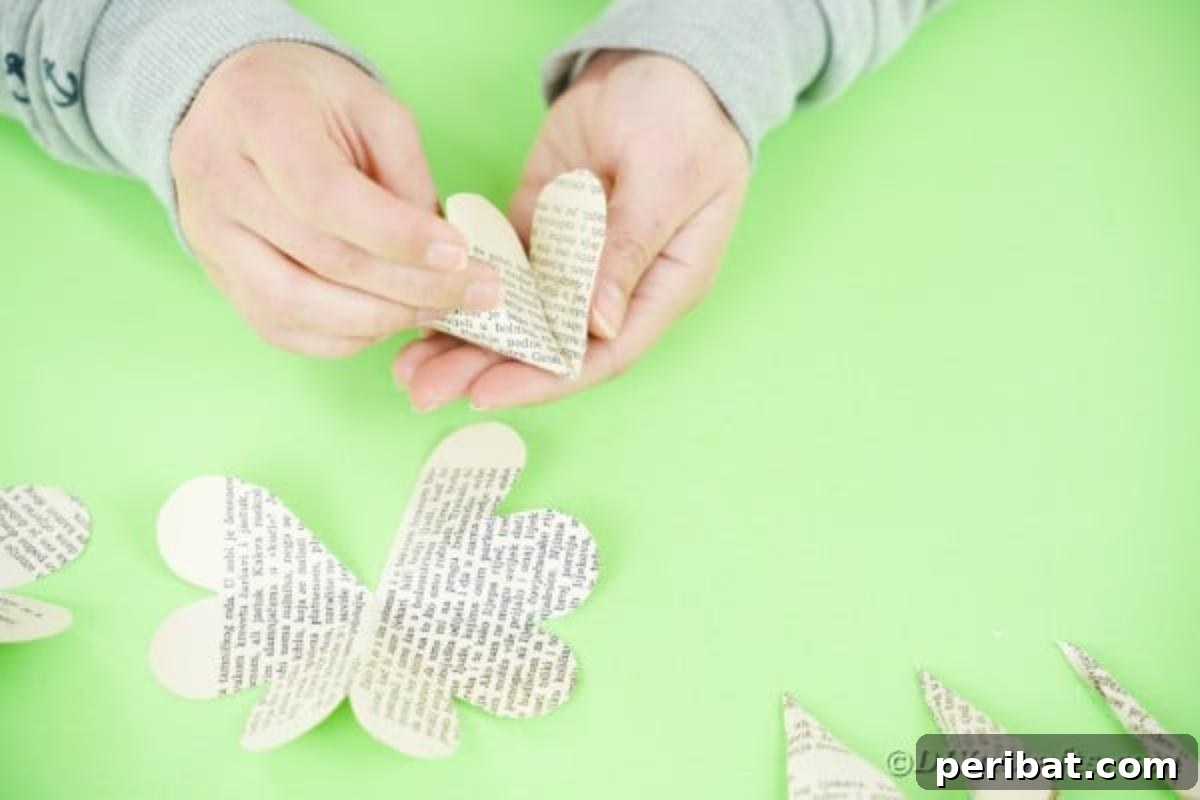 Hands rolling and gluing larger paper flower pieces together