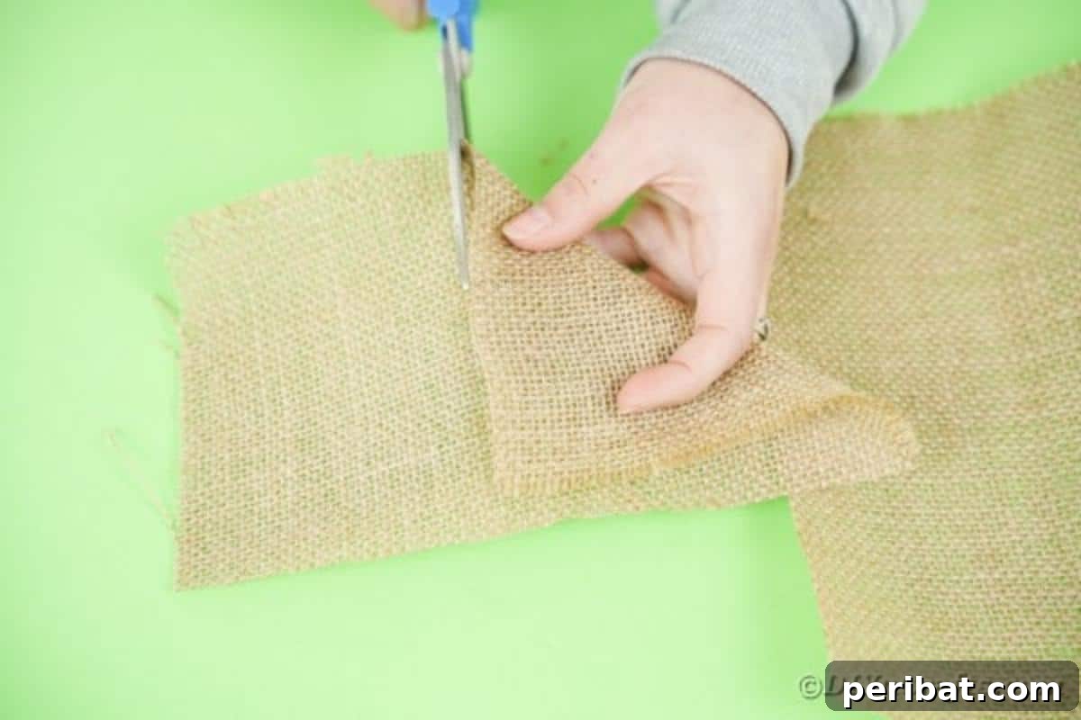 Hands cutting a square piece of burlap fabric