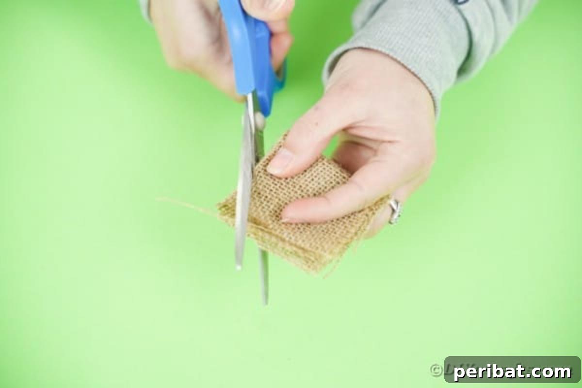 Hands cutting a curved shape from folded burlap fabric
