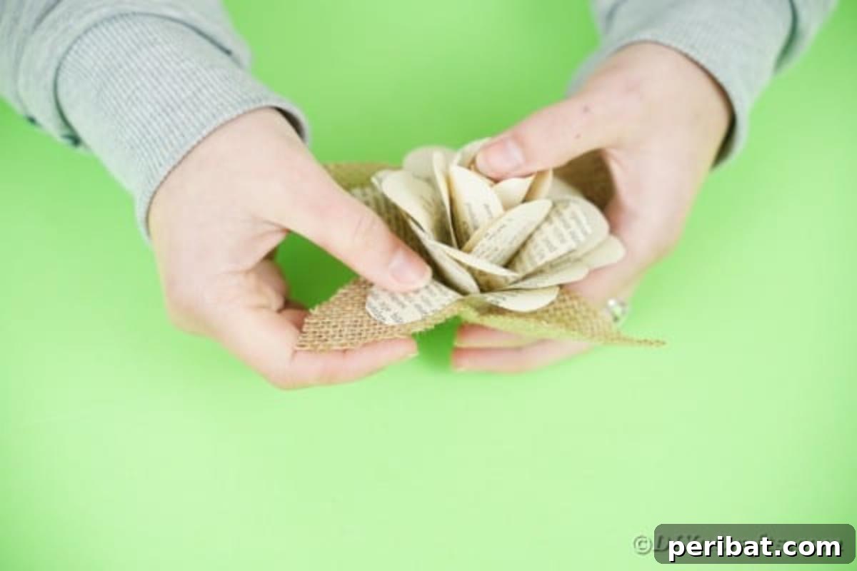 Hands applying glue to secure burlap leaves around the base of a paper flower