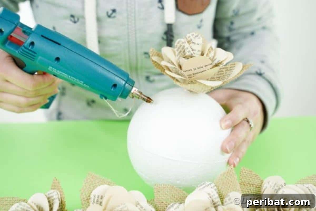 Hands gluing paper flowers onto a Styrofoam ball
