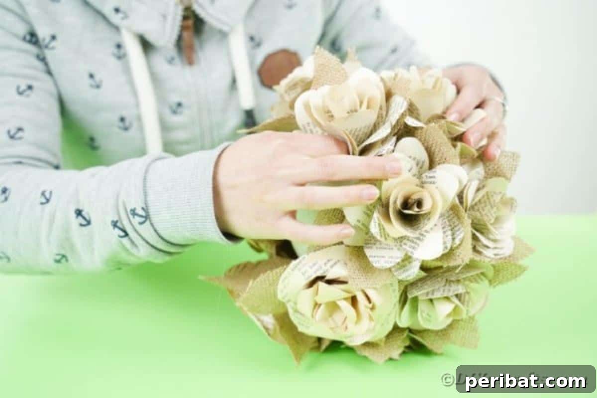 A Styrofoam ball being covered with paper flowers and burlap accents