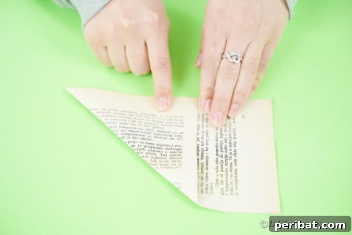 Hands folding a book page to form a triangle