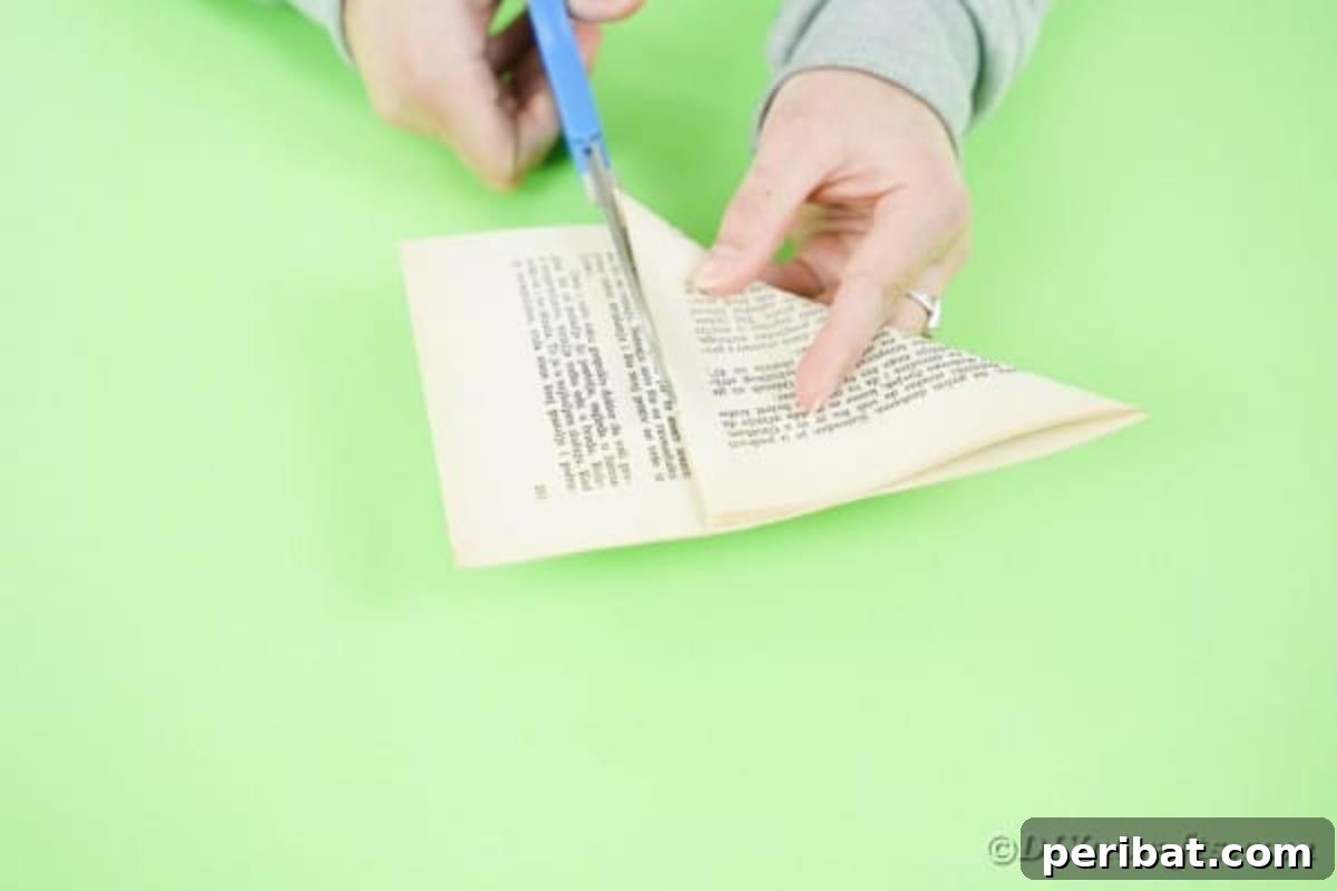 Hands trimming excess paper from a folded book page