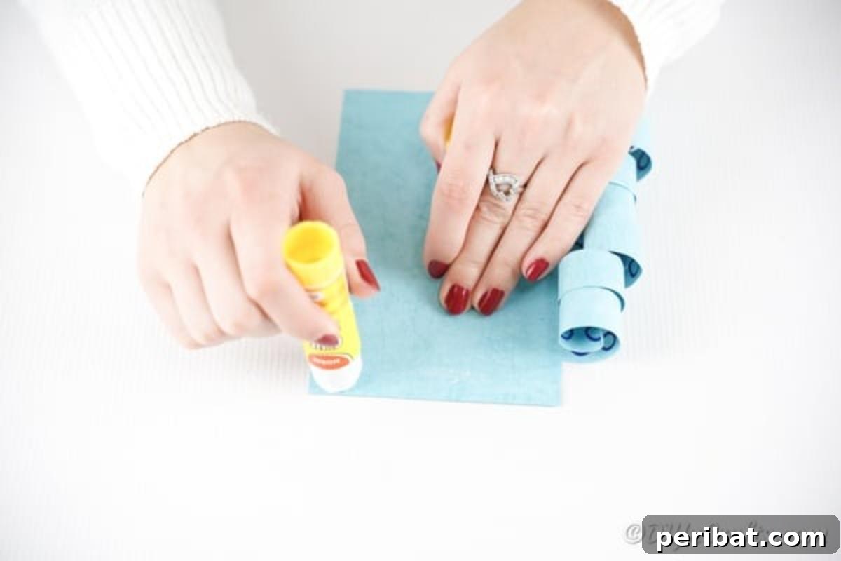 Applying a line of glue along one edge of the blue paper, where a strip was previously removed.