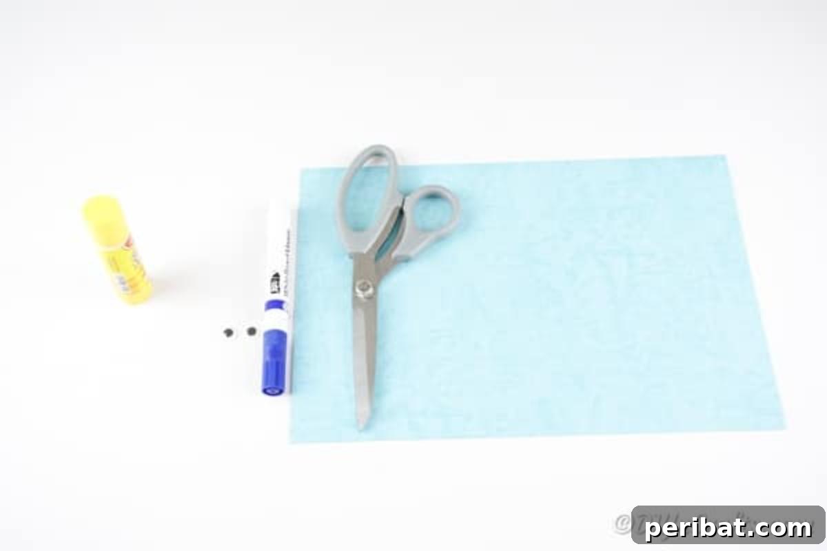 Various craft supplies laid out on a table for making a paper octopus: blue construction paper, marker, googly eyes, glue stick, and scissors.