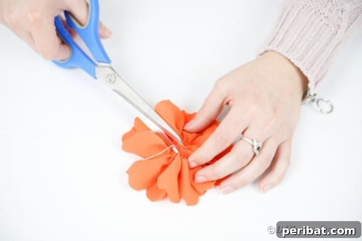 Your Easy Guide to Fabric Flower Bouquets Video 16 Trimming thread from the base of an orange fabric flower