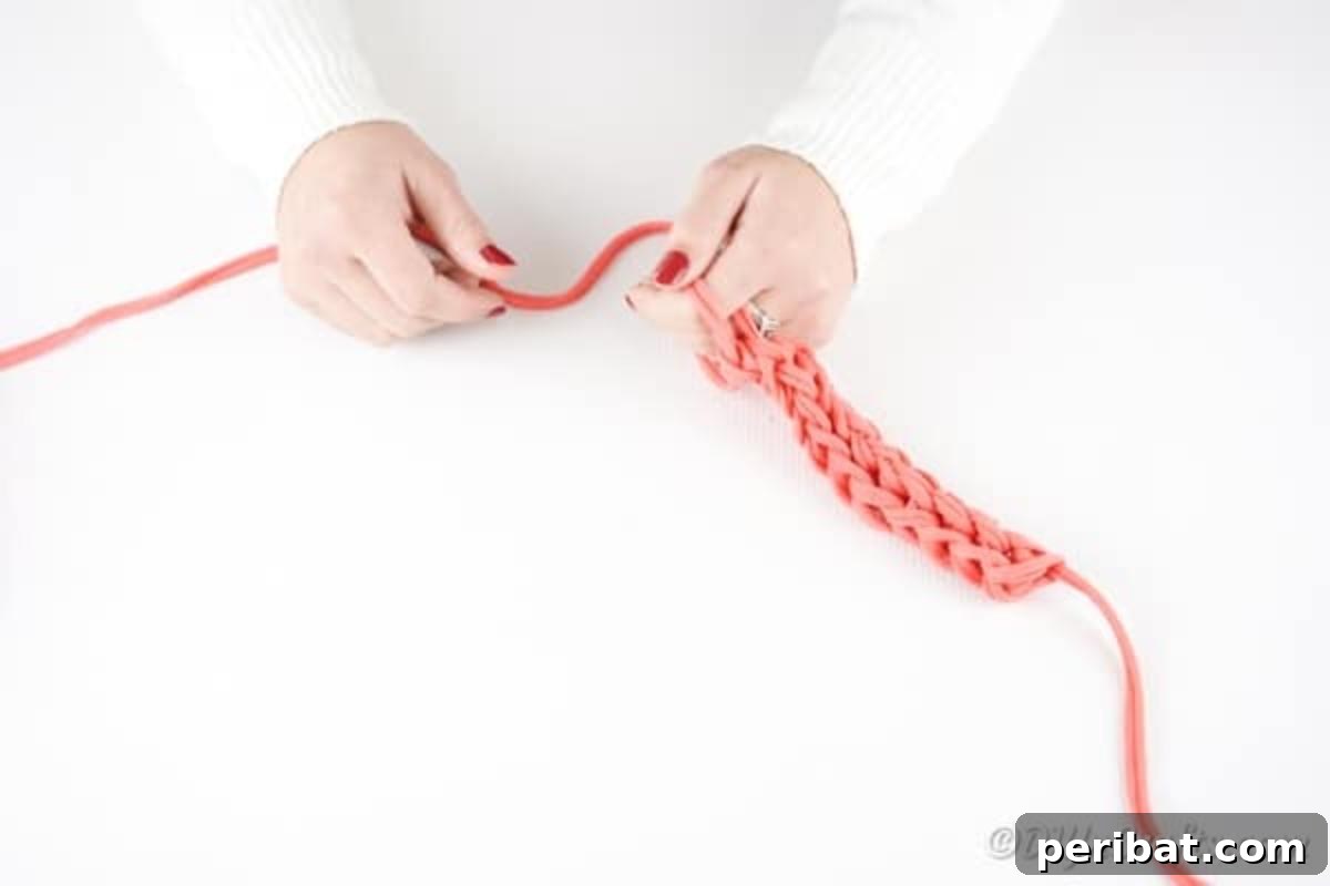 Effortless Elegance: Finger Knit Necklace DIY Video Tutorial 13 The process of tying off the necklace, showing loops being transferred and pulled taut between fingers before the final knot.