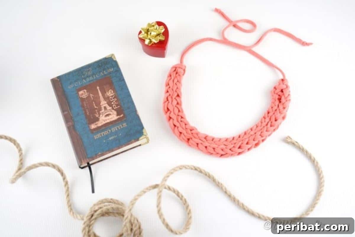 Effortless Elegance: Finger Knit Necklace DIY Video Tutorial 15 The completed finger knit necklace laid out on a white surface next to a book, ready to be worn.