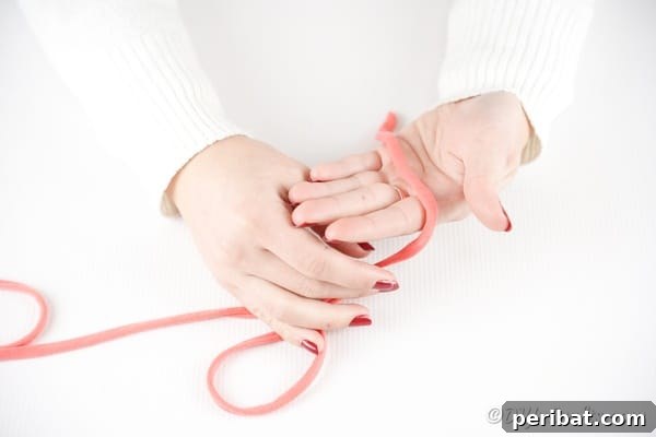 Effortless Elegance: Finger Knit Necklace DIY Video Tutorial 18 The process of weaving pink yarn continues, showing the yarn crisscrossing fingers.