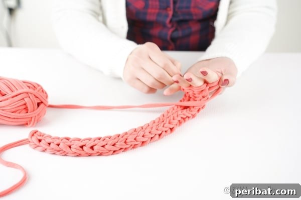 Effortless Elegance: Finger Knit Necklace DIY Video Tutorial 23 Detailed shot of the finger knitting process with pink yarn, emphasizing the loops and texture.