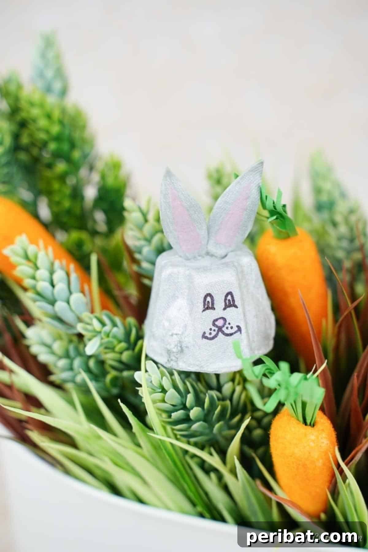 Adorable Upcycled Egg Carton Easter Bunny Craft 4 An adorable egg carton bunny nestled within a miniature woven basket, surrounded by lush greenery, evoking a rustic and natural Easter aesthetic perfect for tabletop decor.