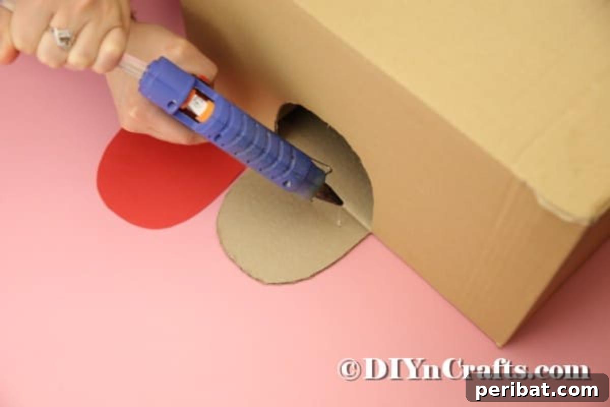 Hoppy Easter Box Ball Toss 12 Gluing the red paper tongue onto the cardboard flap.