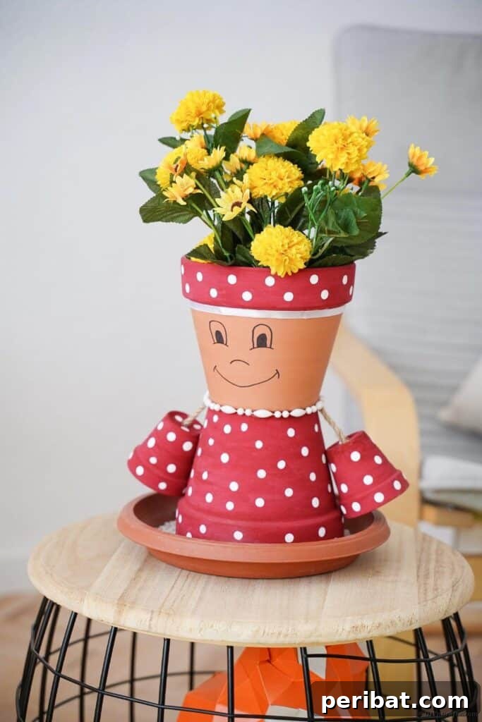 Upcycled pink and white polka dot clay pot person on a stool
