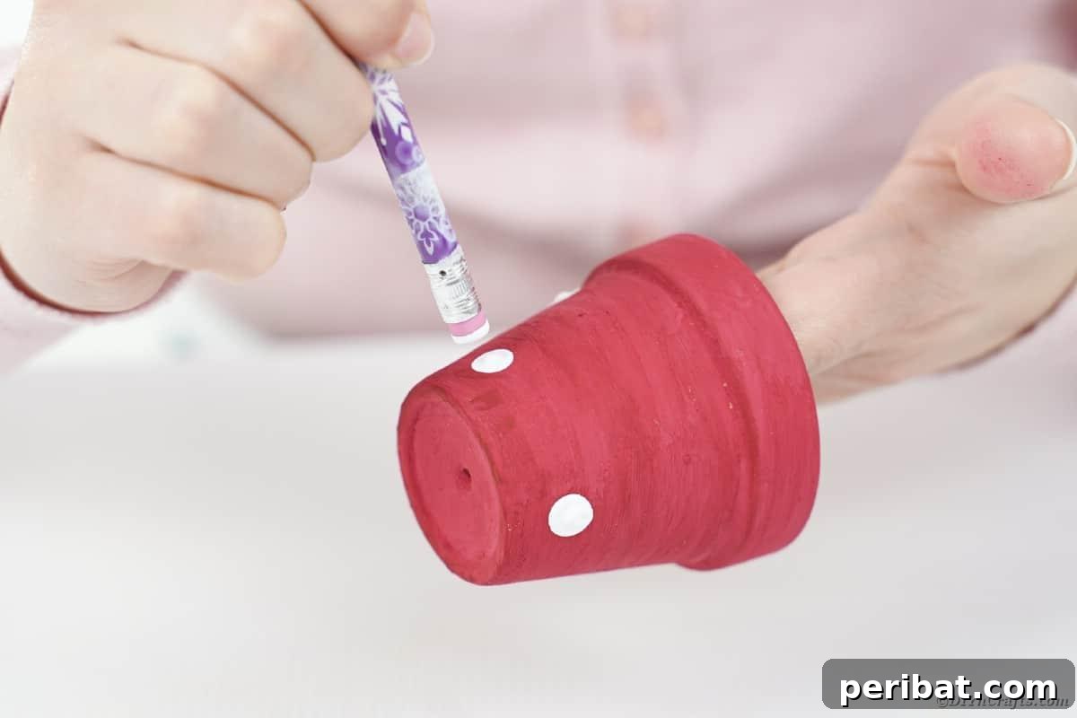 Adding white polka dots to a pink painted flower pot