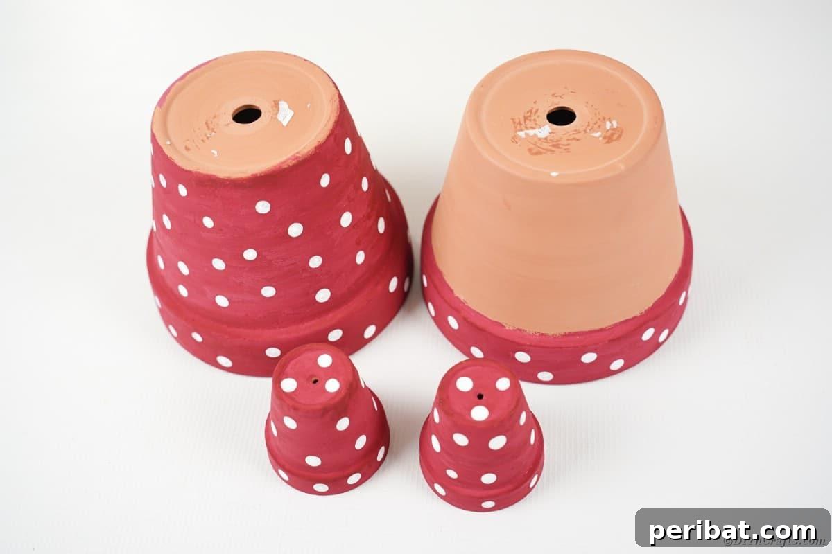 Four painted flower pots with polka dots drying on a white table