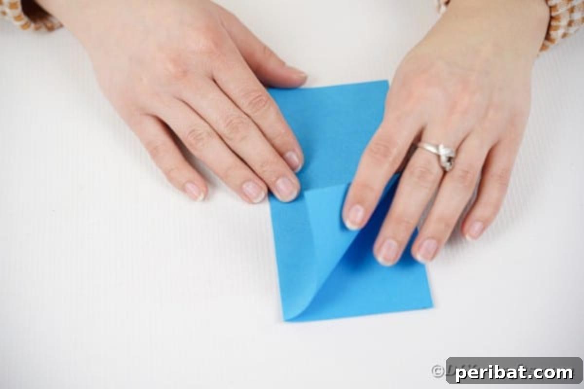 Vibrant DIY Paper Straw Desk Caddy 15 A square piece of paper neatly folded in half on a table surface.