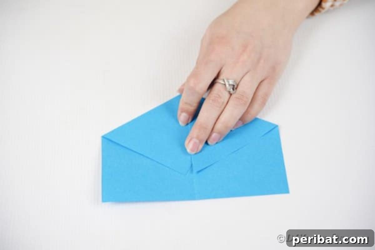 Vibrant DIY Paper Straw Desk Caddy 16 A piece of paper folded into a triangle, with its top point then folded down.