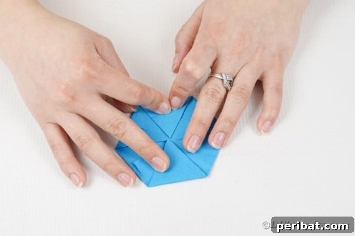 Vibrant DIY Paper Straw Desk Caddy 20 A close-up of hands completing the final folds on a piece of paper, forming a neat hexagonal base.