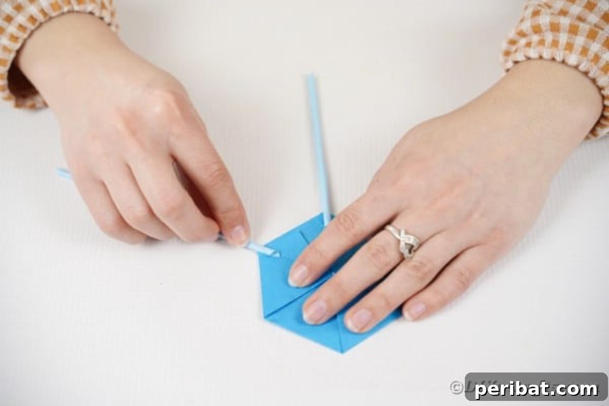 Vibrant DIY Paper Straw Desk Caddy 22 A hand is gluing a colorful paper straw onto a point of the hexagonal paper base.