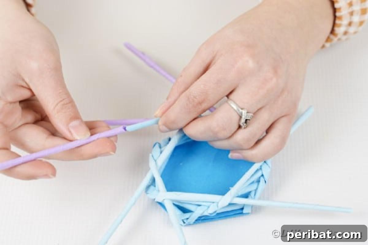 Vibrant DIY Paper Straw Desk Caddy 26 A purple paper straw is being added to the blue section of the weaving pattern, transitioning colors.