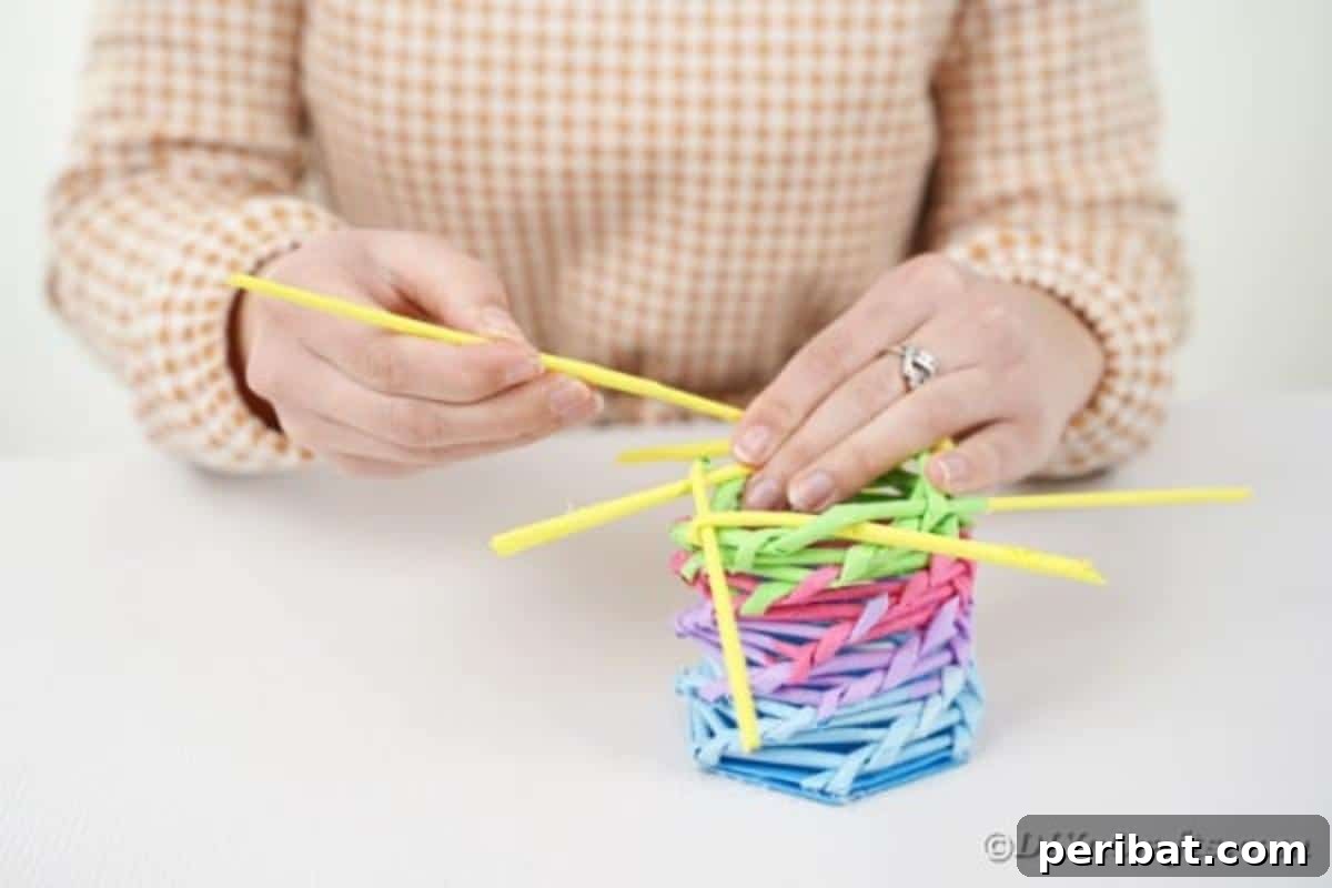 Vibrant DIY Paper Straw Desk Caddy 27 A yellow paper straw is being added to the weaving pattern, continuing the rainbow color progression on the organizer.