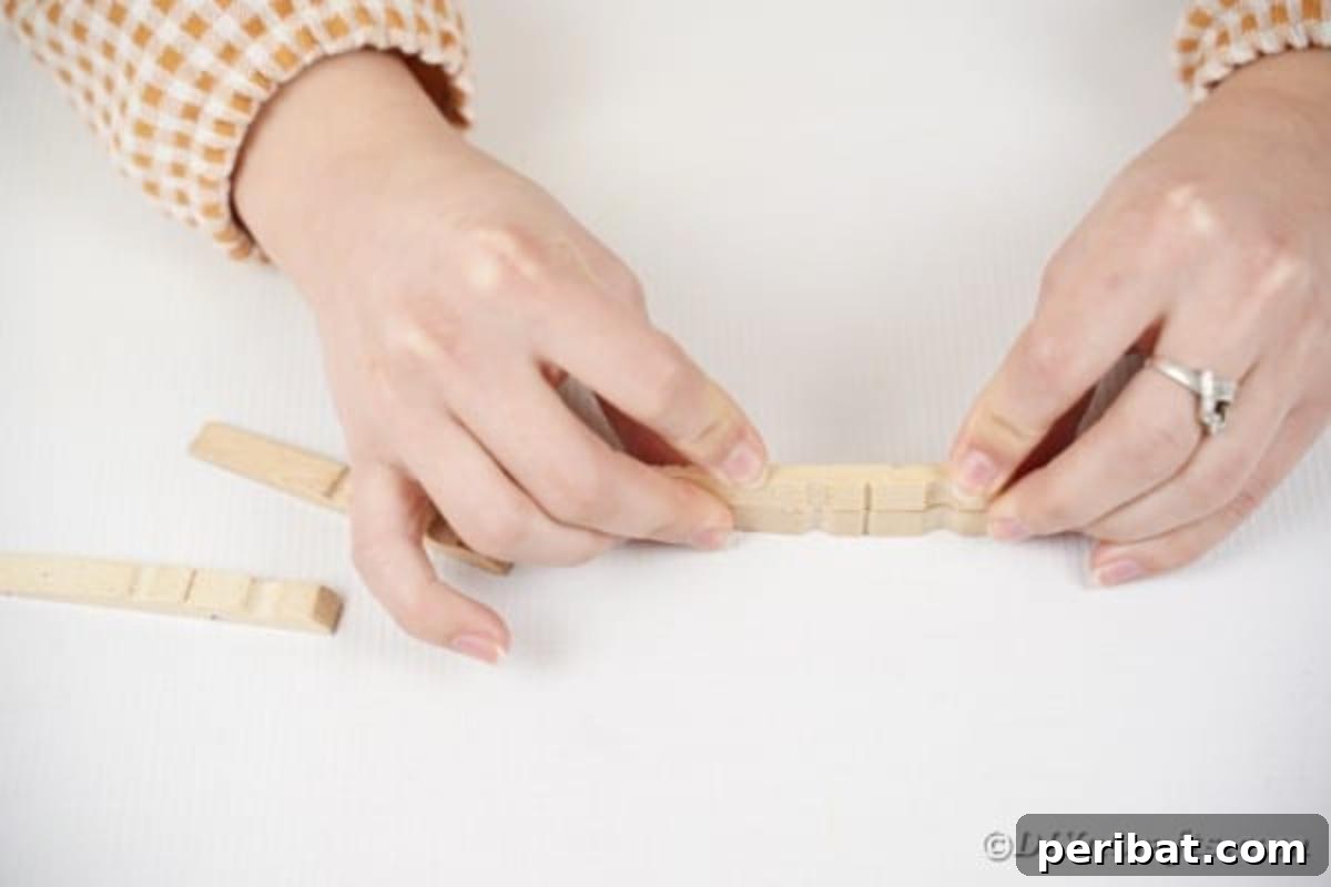 Chic Repurposed Clothespin Napkin Rack 12 A single wooden clothespin half is being carefully glued to another, demonstrating the creation of a base block.