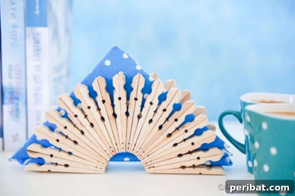 Chic Repurposed Clothespin Napkin Rack 3 The finished clothespin napkin holder stands proudly against a serene blue surface, ready to hold napkins.