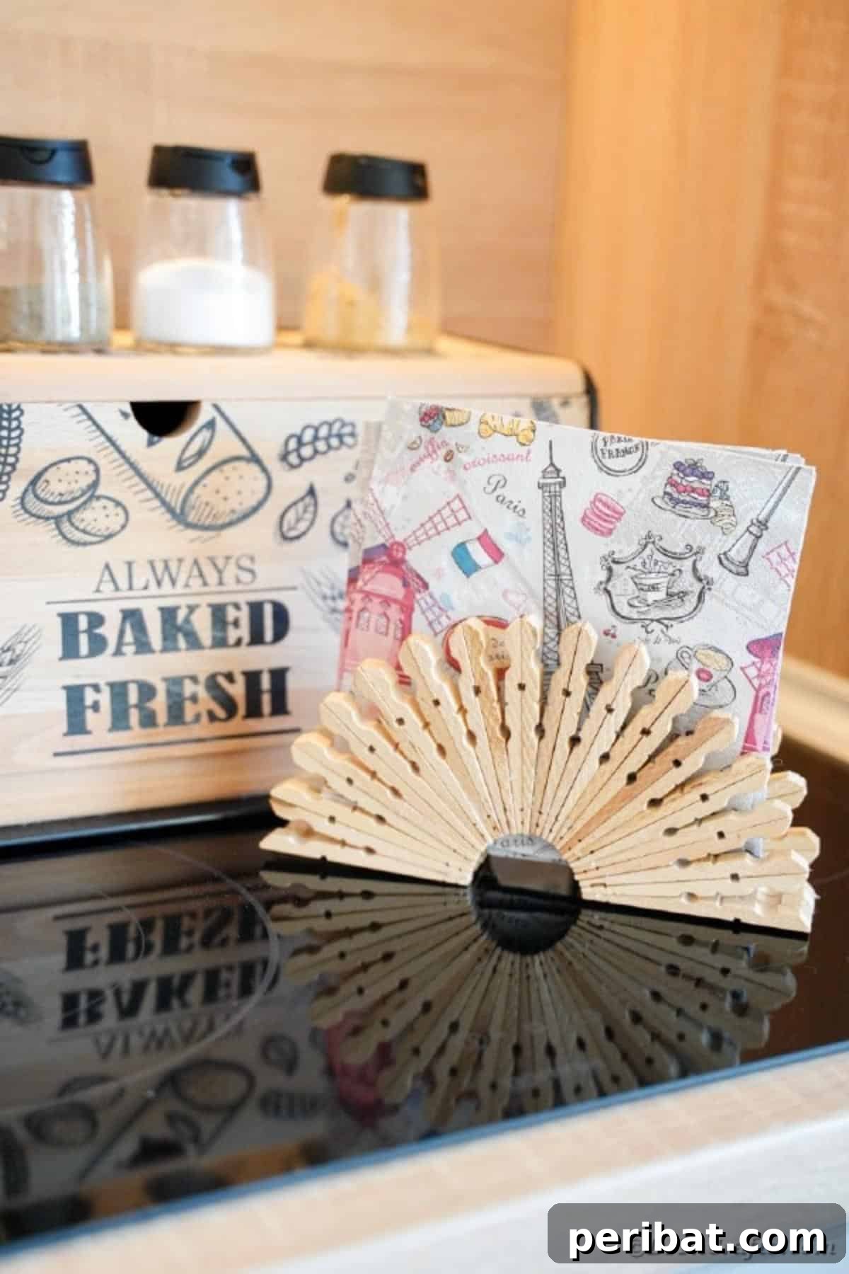 Chic Repurposed Clothespin Napkin Rack 4 A beautifully crafted clothespin napkin holder rests in front of a rustic bread box, emphasizing its farmhouse charm.