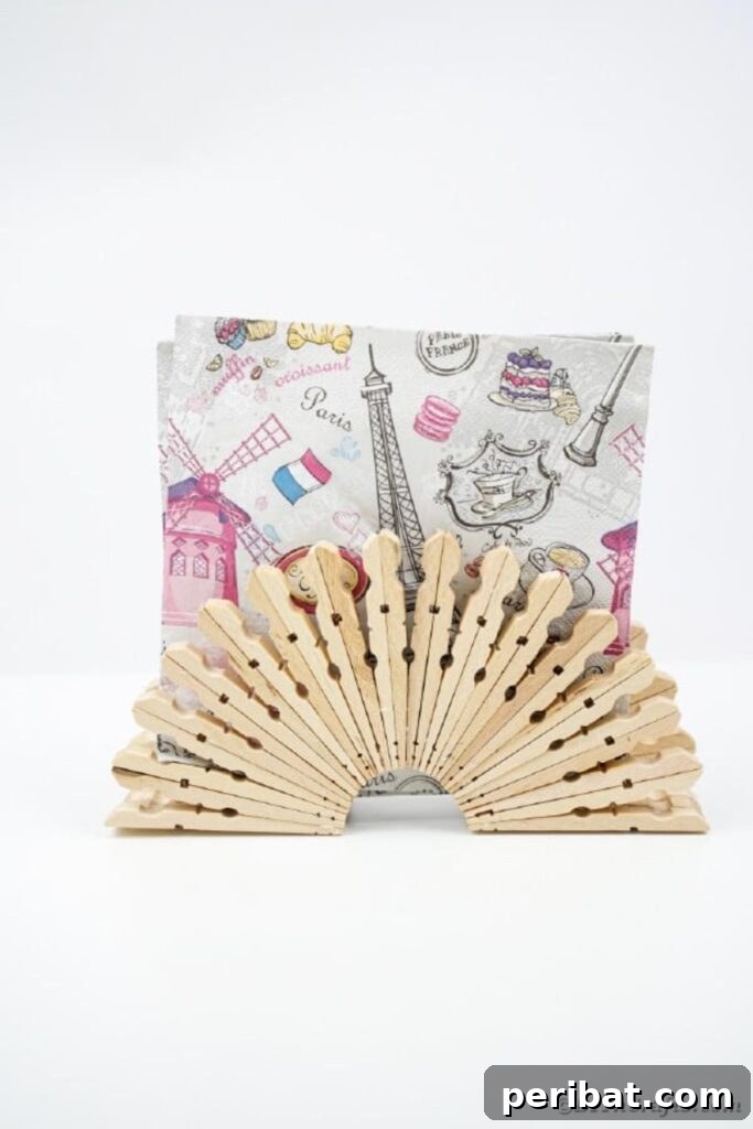 Chic Repurposed Clothespin Napkin Rack 17 A unique clothespin napkin holder on a white surface, holding napkins adorned with a Paris theme.
