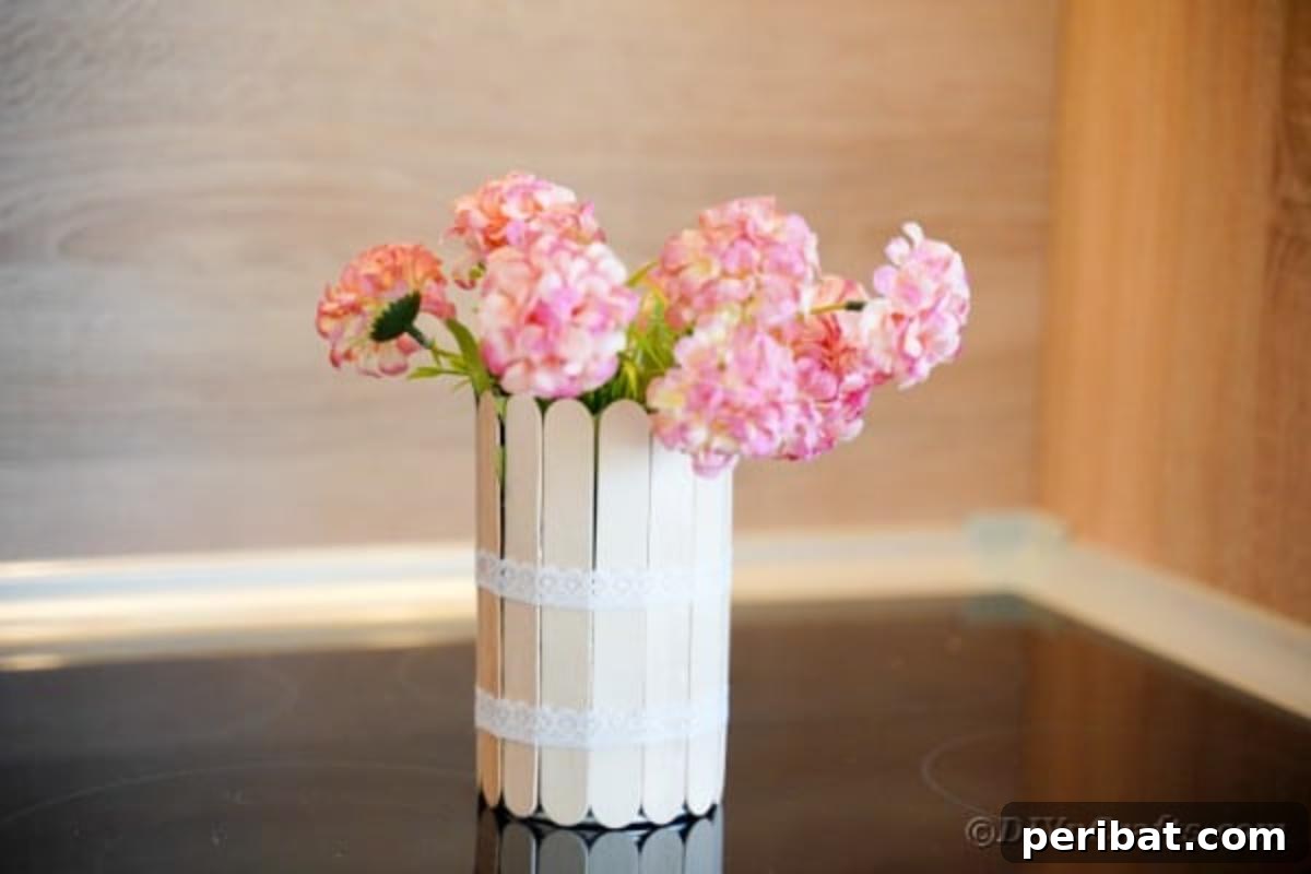 Transform Tin Cans into a Rustic Craft Stick Organizer Video Tutorial 5 Craft stick can with pink flowers on a rustic wood table