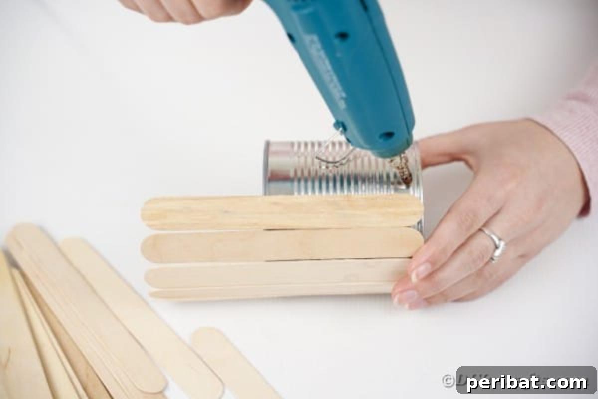 Transform Tin Cans into a Rustic Craft Stick Organizer Video Tutorial 9 First craft stick being glued onto a tin can