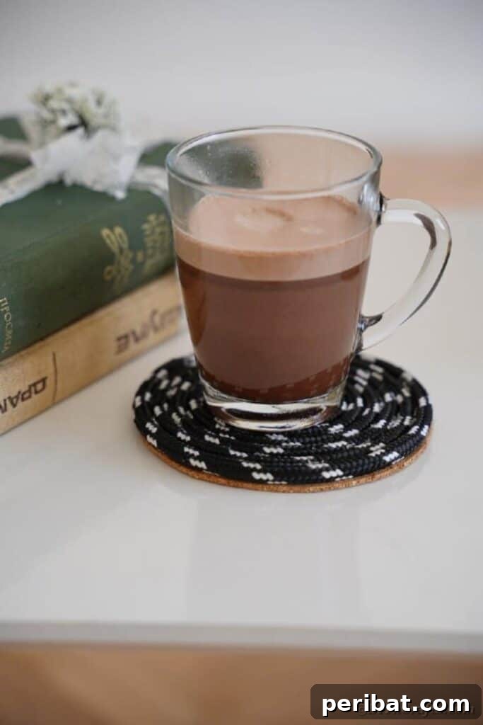 Glass of coffee on black coaster on side table by books