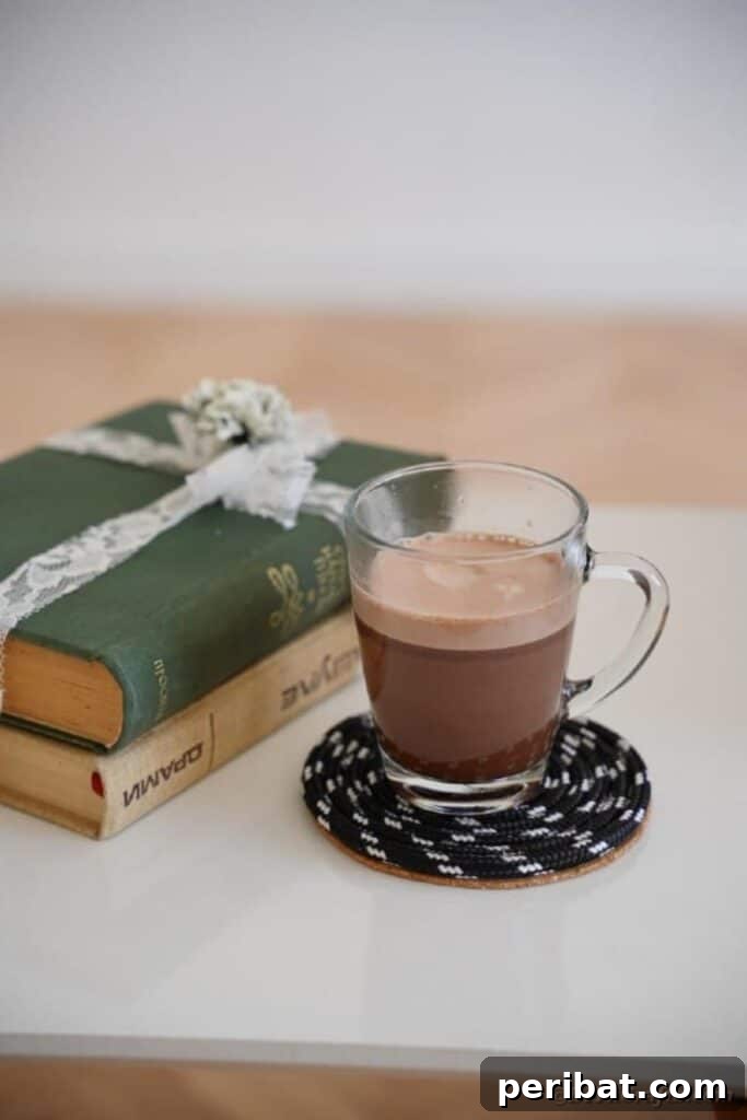 Glass of coffee on black coaster on side table by books