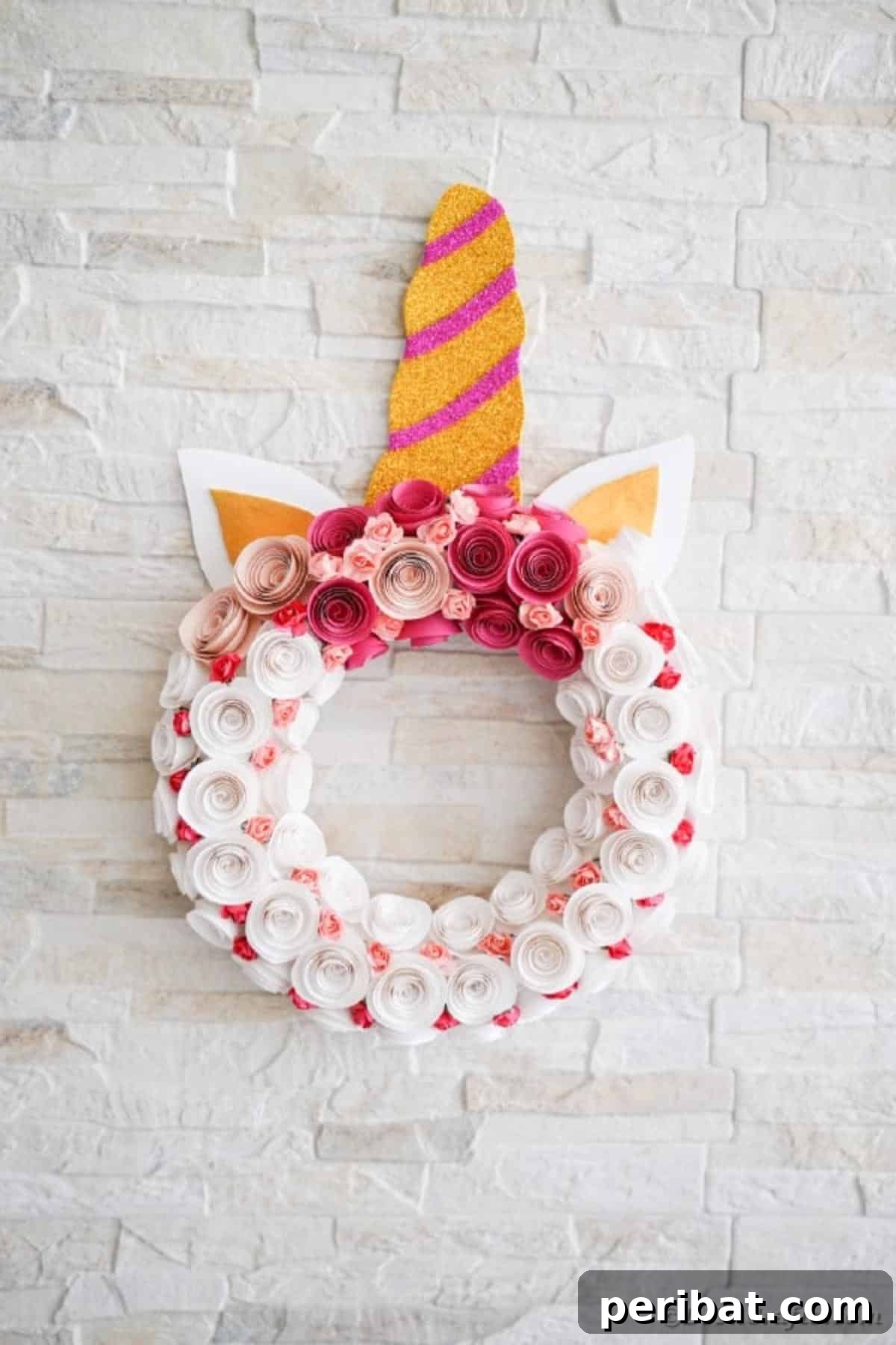 Enchanting Quilled Unicorn Wreath 4 A close-up shot of the finished paper unicorn wreath, adorned with charming paper flowers and its characteristic horn and ears, displayed against a rustic brick wall to show texture contrast.