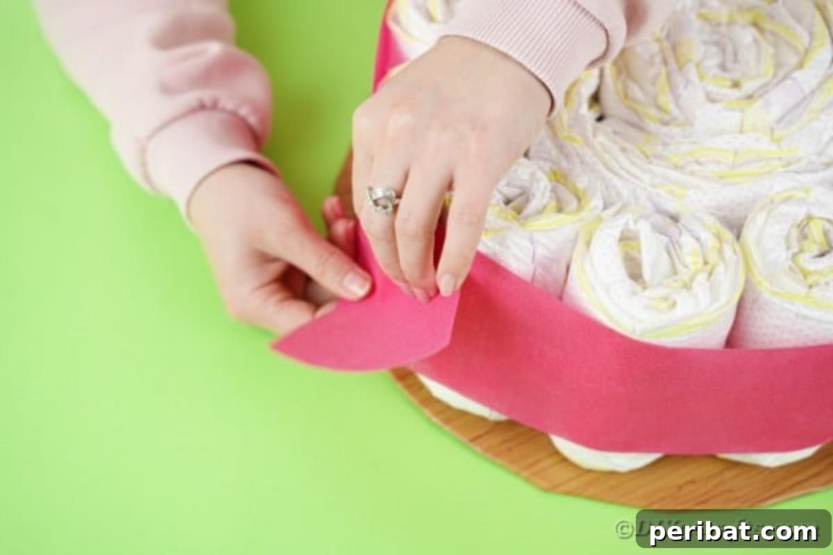 Kraliyet Bez Şato: Bebek Duşu İçin Özel El Yapımı Hediye 13 Stapling decorative paper onto the diaper cake base for a clean finish
