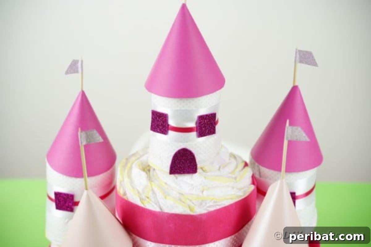 Kraliyet Bez Şato: Bebek Duşu İçin Özel El Yapımı Hediye 7 Castle diaper cake adorned with pink ribbons and glitter, resting on a green table