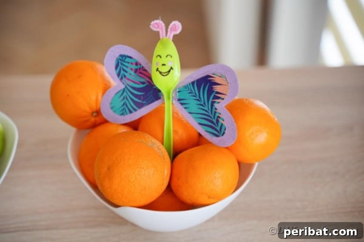 A finished purple upcycled spoon butterfly gracefully positioned among fresh oranges, demonstrating its charm as a decorative item.