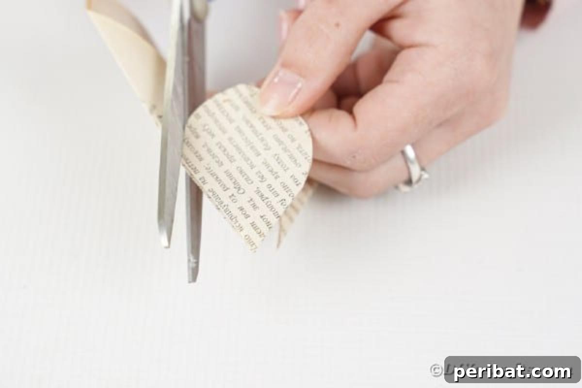 Scissors cutting a rounded shape from folded paper to form flower petals.