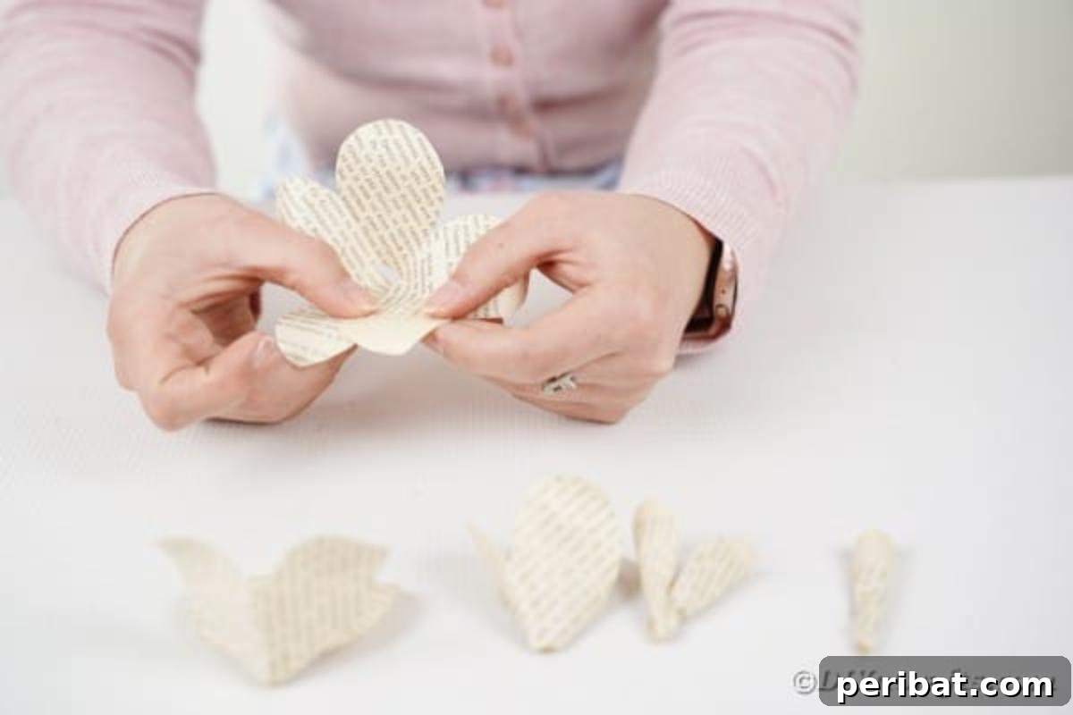A hand gluing paper rose petals together to form a layered flower.