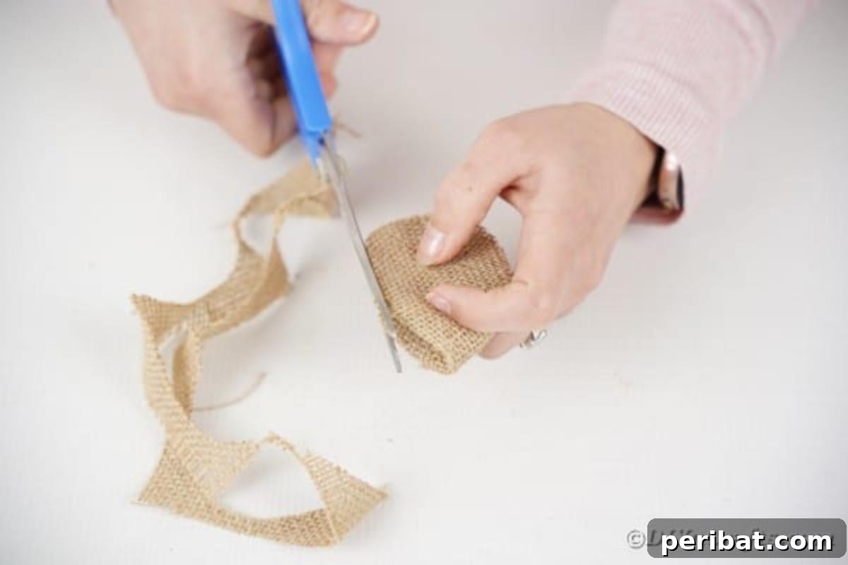 Scissors cutting a leaf shape out of folded burlap fabric.