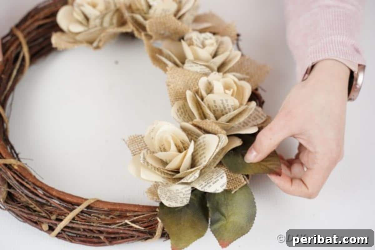 A woman gluing artificial leaves onto the wreath, adding final touches of greenery.