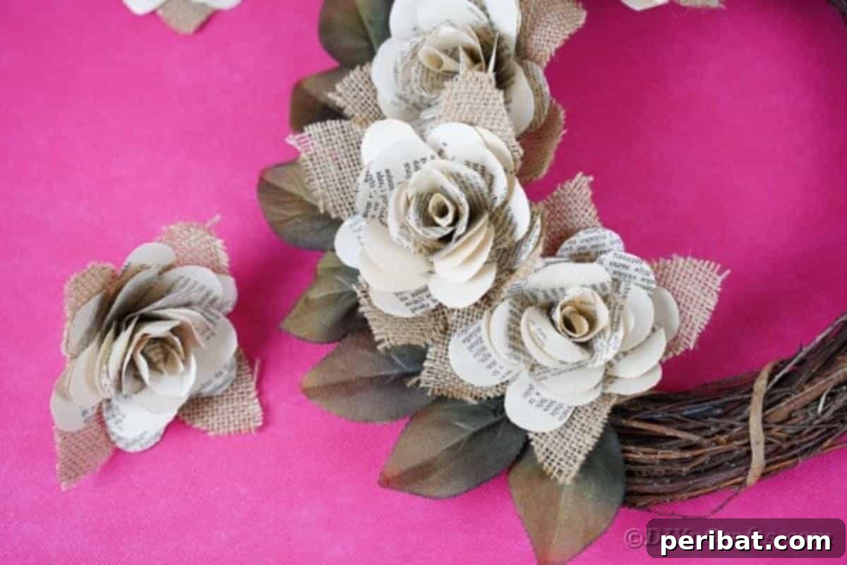 A finished paper rose wreath resting on a pink surface, highlighting the details of the handmade paper flowers and burlap accents.