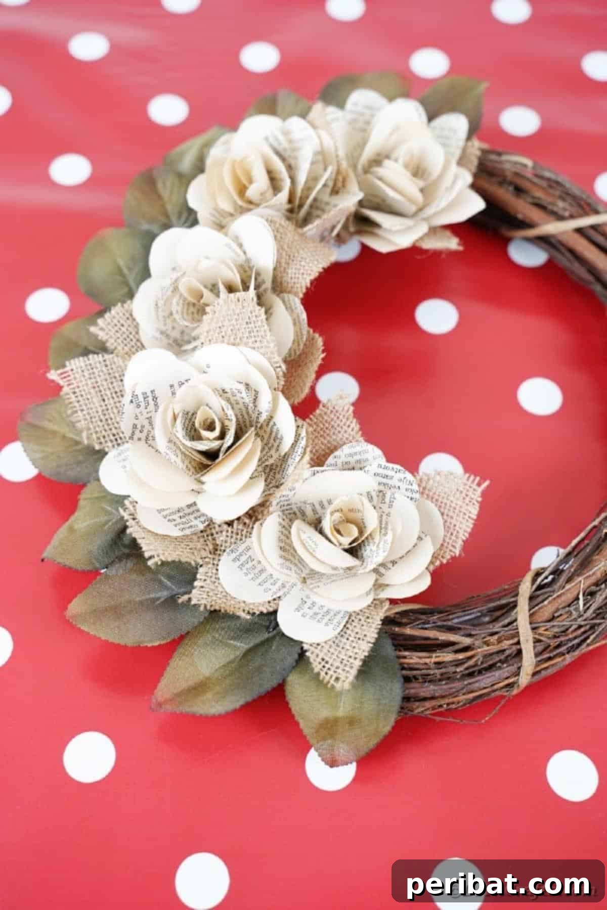 The book page wreath resting on a vibrant red polka dot table, demonstrating its ability to complement various decor styles.