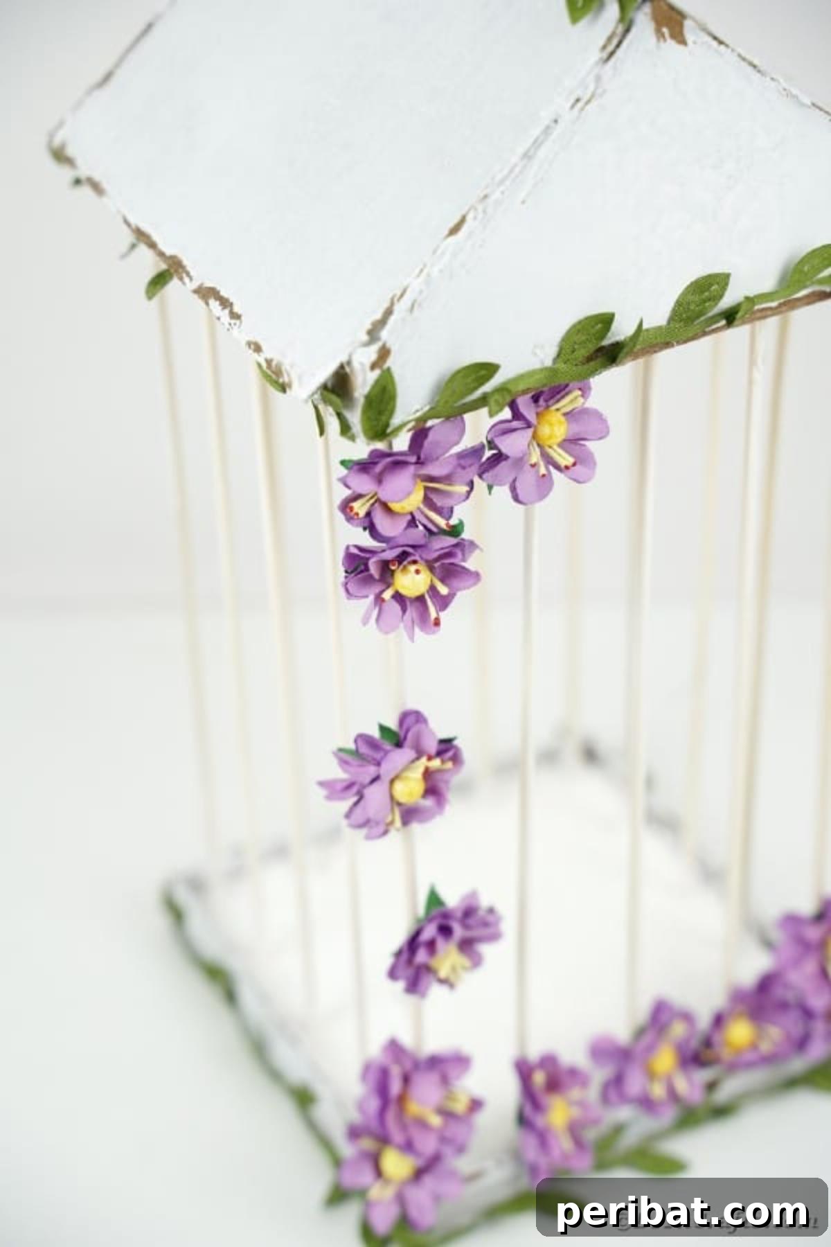 Crafting a Beautiful Floral Birdcage Display 22 White Birdcage with Purple Flowers on White Surface - The finished DIY birdcage ready for display.