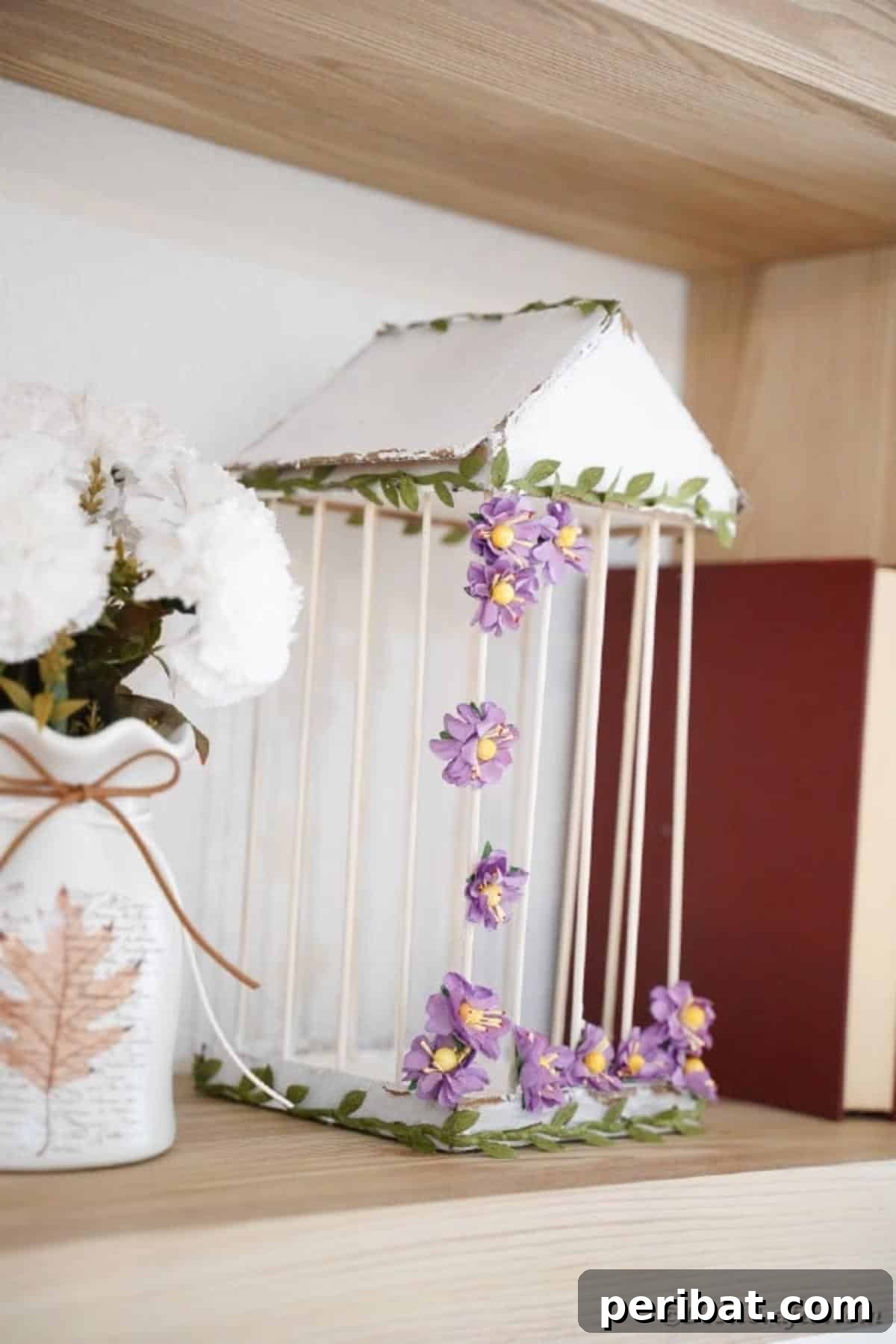 Crafting a Beautiful Floral Birdcage Display 24 White Birdcage with Purple Flowers on Bookshelf - A beautifully crafted DIY birdcage with a distressed white finish, adorned with delicate purple flowers and green foliage, sits elegantly on a bookshelf, adding a touch of rustic charm to the room. Ideal for personalized home accents.