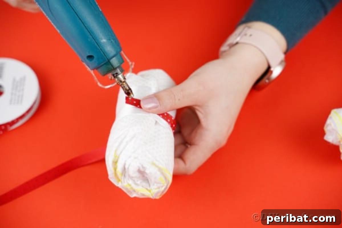 Thin red ribbon being carefully glued onto a diaper with white ribbon