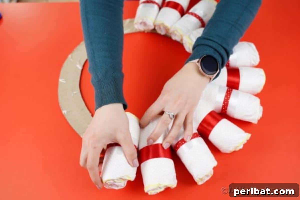 Diapers with alternating red ribbon designs being secured to the wreath form